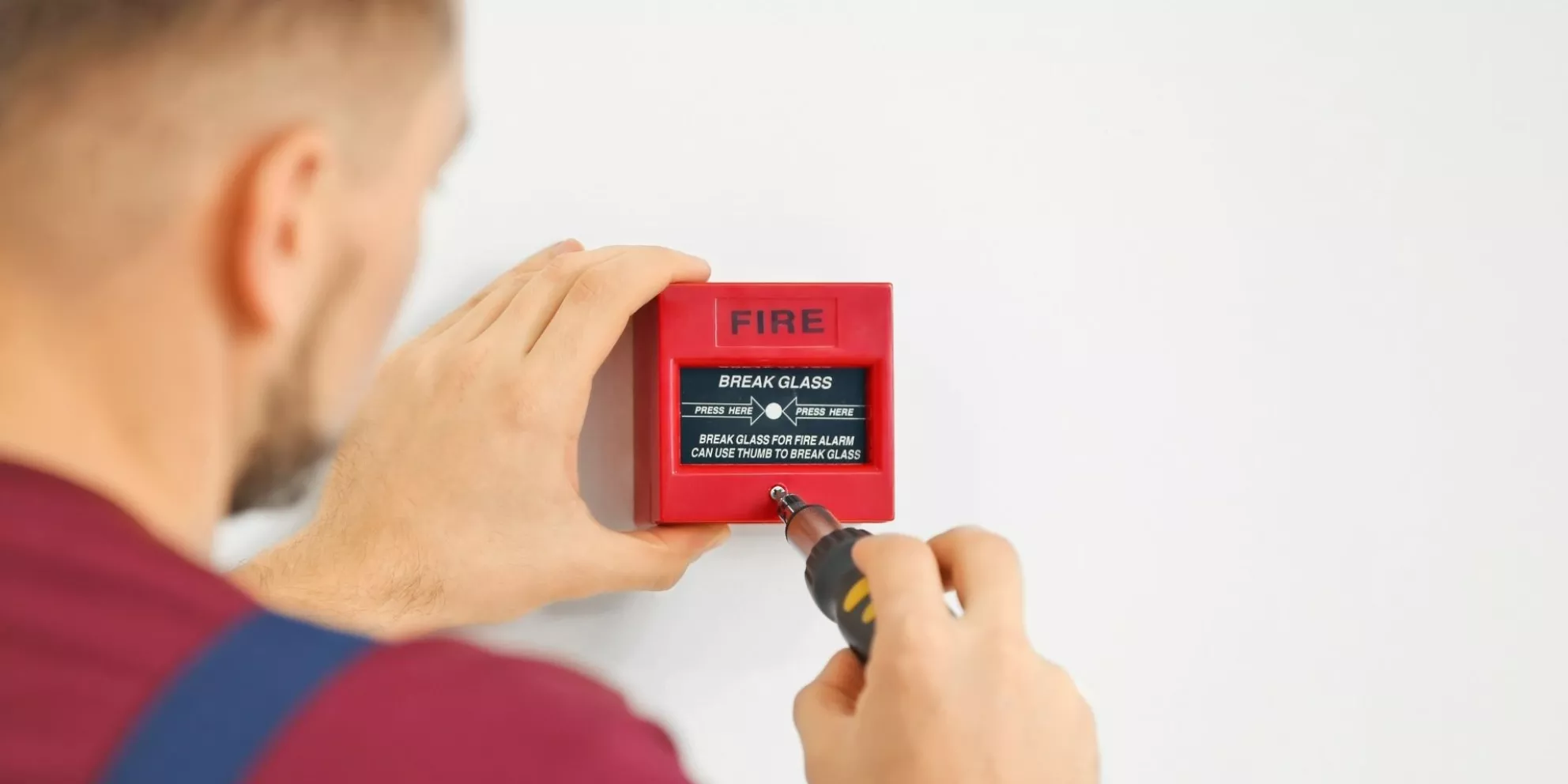 Technician installs fire alarm on wall